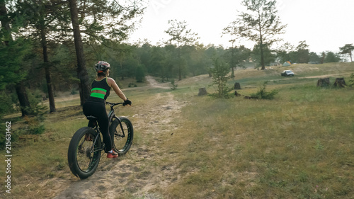 Fat bike also called fatbike or fat-tire bike in summer riding in the forest. Beautiful girl and her bicycle in the forest. She rolls her bike and poses to the operator.