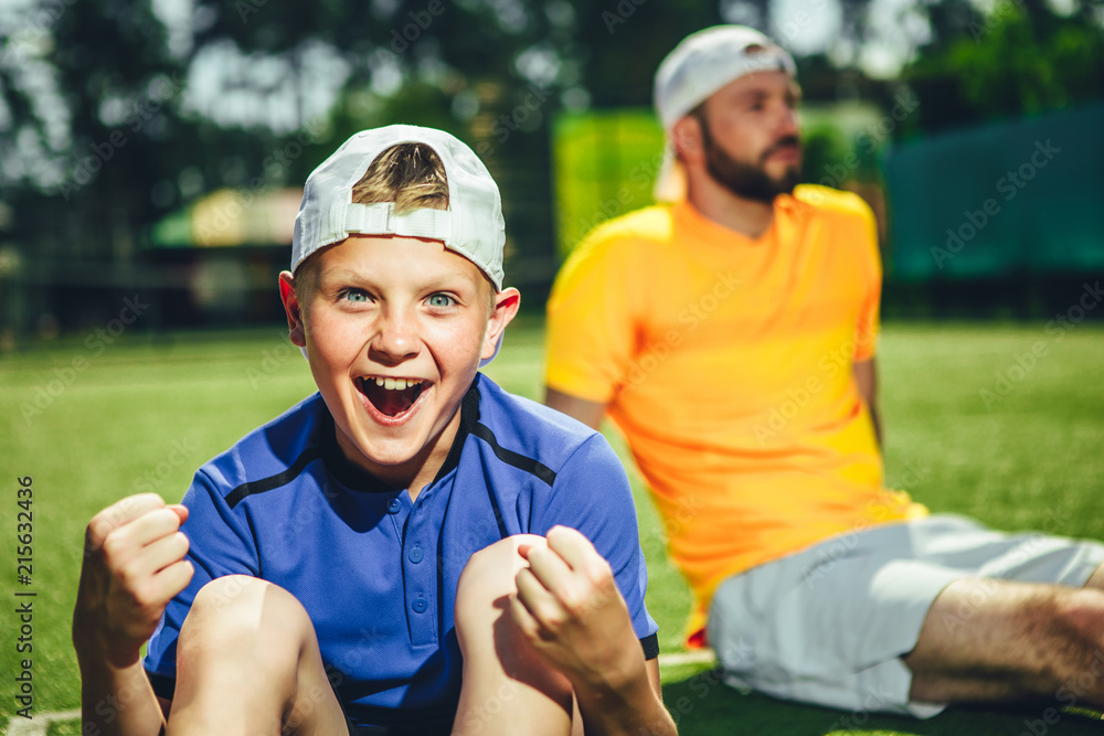 We did it. Portrait of satisfied child shouting while gesticulating hands. Happy trainer relaxing after training on ground We did it. Portrait of satisfied child shouting while gesticulating hands. Happy trainer relaxing after training on ground
