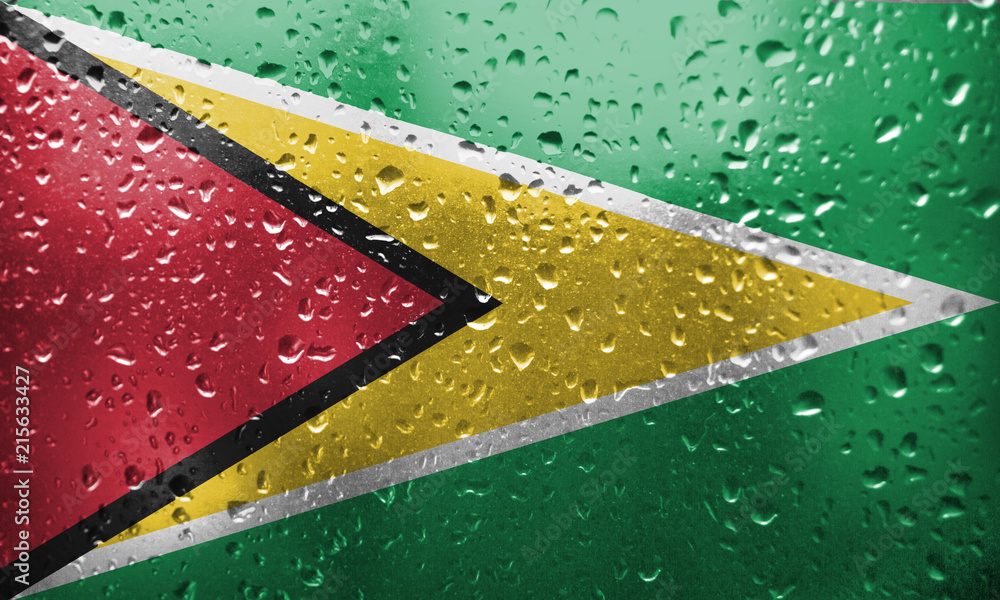 Texture of Guyana  flag on the glass with drops of rain.