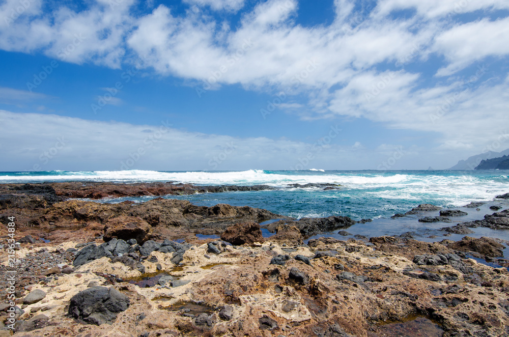 Beautiful seascape with view on the Atlantic Ocean, blue sky with white clouds and stone wild beach near Punta del Hidalgo and Anaga Rural Park. Tenerife North. Canary Islands, Spain.