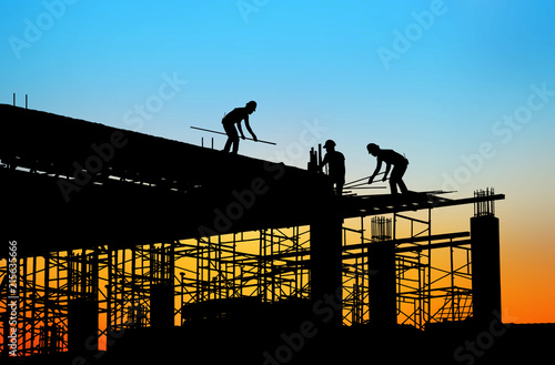 silhouette construction team working on high ground over blurred background sunset sky.