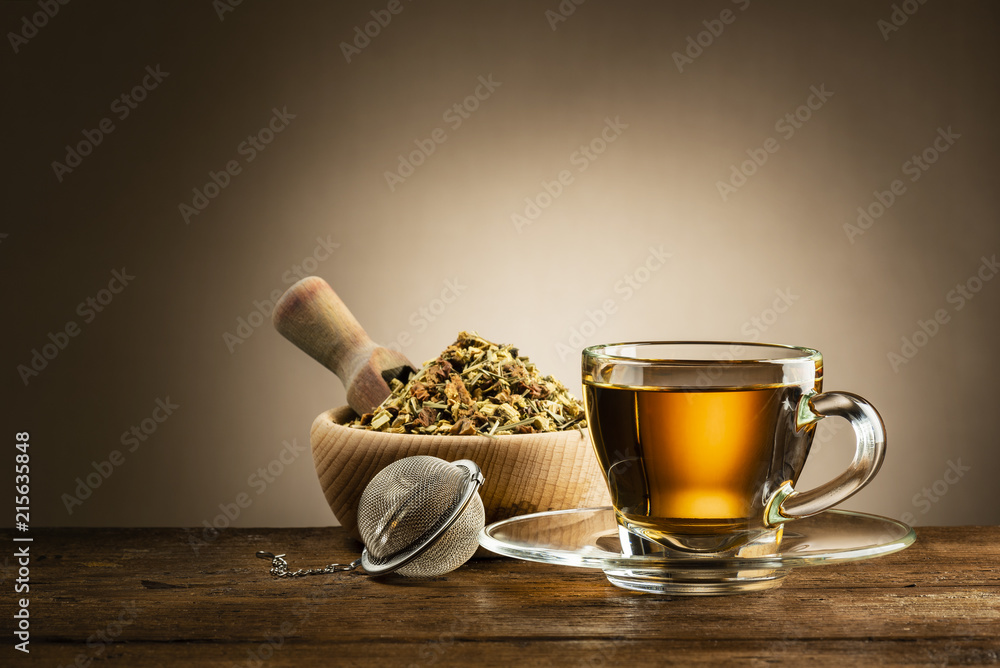 glass cup of tea with infuser and herbal tea on wooden table - obrazy, fototapety, plakaty 