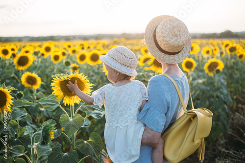 Happy mother and her little daughter in the sunflower field