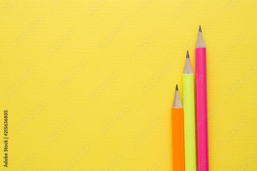 Obraz premium Bright colored pencils on yellow background. Copy space