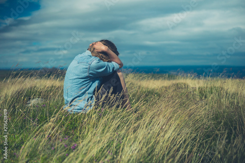 Sad woman in field on windy day © LoloStock