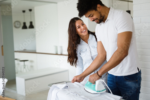 Young couple at home doing hosehold chores and ironing