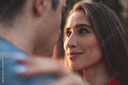 Close up focus on female face. Young girl is looking at man with true love and care. She is enjoying his company 