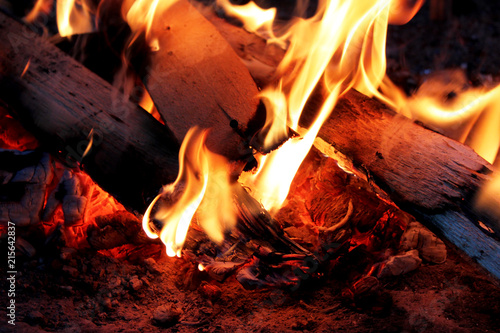 Yellow bright bonfire on black background, horizontal view. Orange flame of campfire. Night.