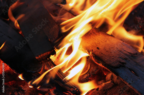 Yellow bright bonfire on black background, horizontal view. Orange flame of campfire. Night.