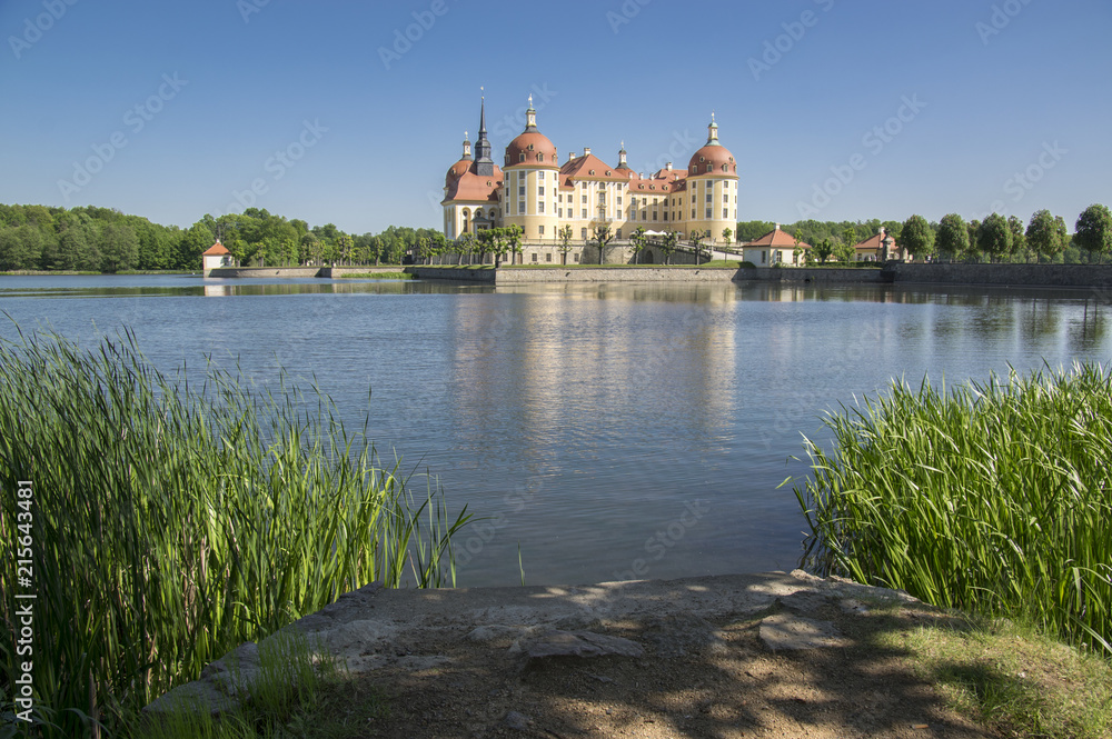 Castle Moritzburg in Saxony near Dresden in Germany surrounded by pond, reflection blue lake, blue sky