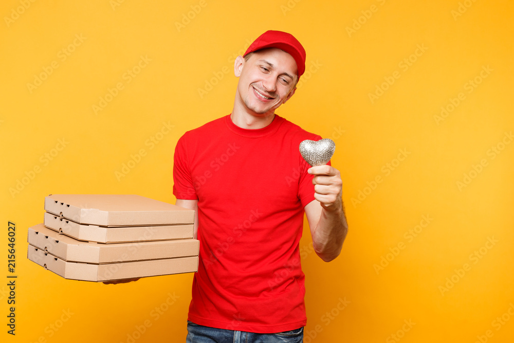 Delivery man in red cap t-shirt giving food order pizza boxes isolated on yellow background. Male employee pizzaman courier in uniform holding heart italian pizza in cardboard flatbox. Service concept Delivery man in red cap t-shirt giving food order pizza boxes isolated on yellow background. Male employee pizzaman courier in uniform holding heart italian pizza in cardboard flatbox. Service concept