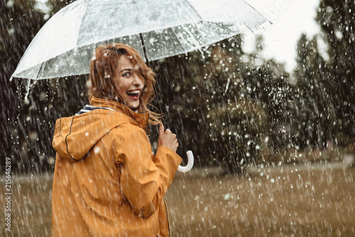 Fotografia Cheerful pretty girl holding umbrella while strolling outside