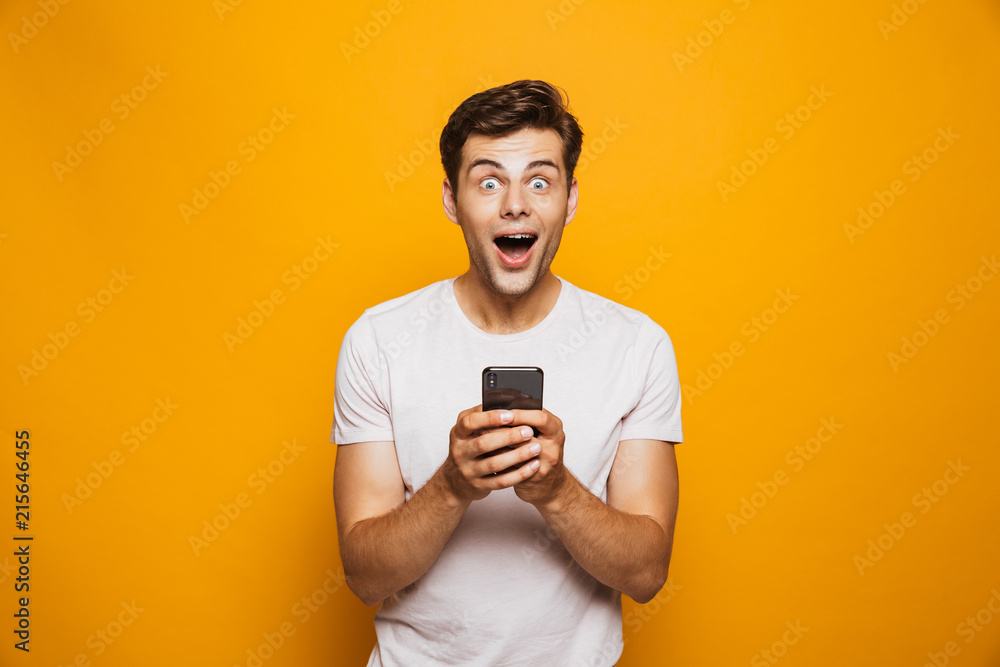 Portrait of a shocked young man holding mobile phone Portrait of a shocked young man holding mobile phone