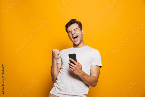 Portrait of a joyful young man holding mobile phone