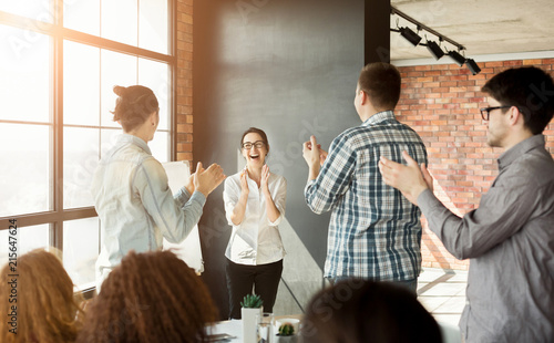 Young team clapping hands to colleague at meeting photo