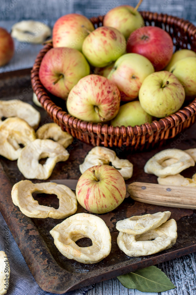 Dessert. Dried apple rings on an old baking sheet, next to a wicker brown basket with fresh ripe apples. Dessert. Dried apple rings on an old baking sheet, next to a wicker brown basket with fresh ripe apples.