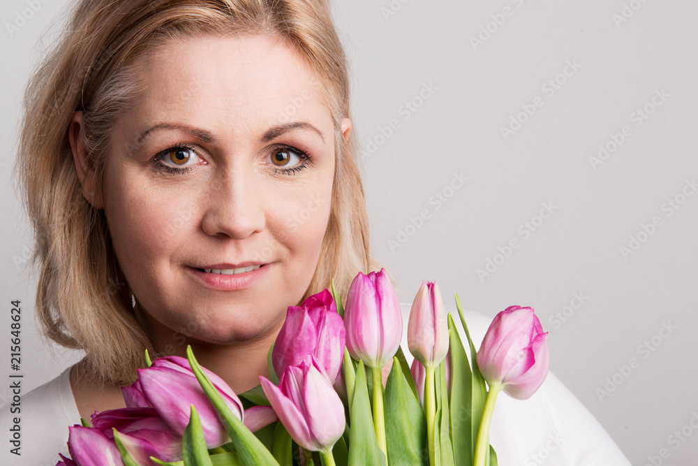 Portrait of an attractive overweight woman with tulips in studio on a white background. Portrait of an attractive overweight woman with tulips in studio on a white background.