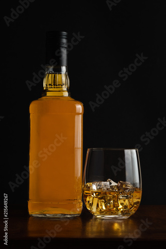 Glass of whiskey and it's bottle with dark background