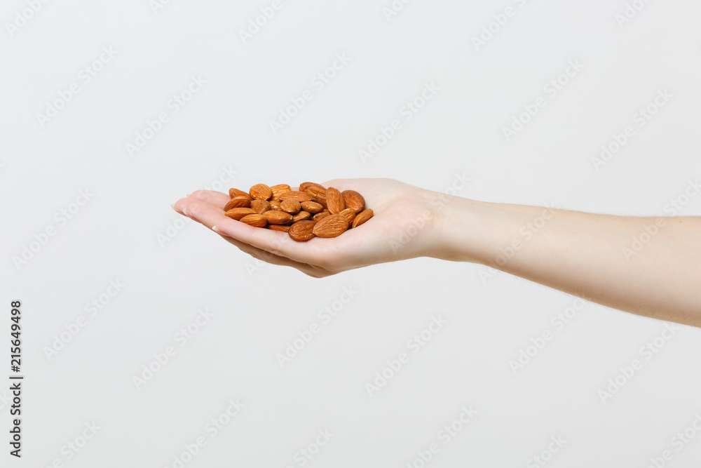 Close up female hold in hand brown unprocessed almonds nuts isolated on white background. Proper nutrition, vegan food vegetarian eating, healthy lifestyle dieting concept. Copy space advertising area Close up female hold in hand brown unprocessed almonds nuts isolated on white background. Proper nutrition, vegan food vegetarian eating, healthy lifestyle dieting concept. Copy space advertising area