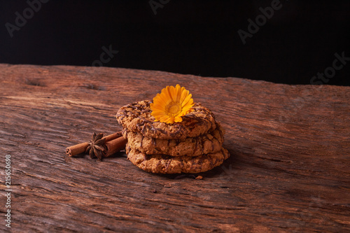 watered chocolate syrup cookies on wooden table. Cute composition with flowers and sticks of cinnamon. Selective focus photo