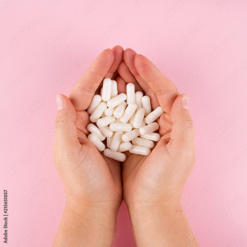 Hands hold pills isolated on pastel coloured background. Medication and prescription pills flat lay background. Hands hold pills isolated on pastel coloured background. Medication and prescription pills flat lay background.