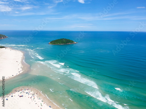  Aerial view of Brazilian beach with blue sky, white clouds, tourists in the sand, green and blue sea.