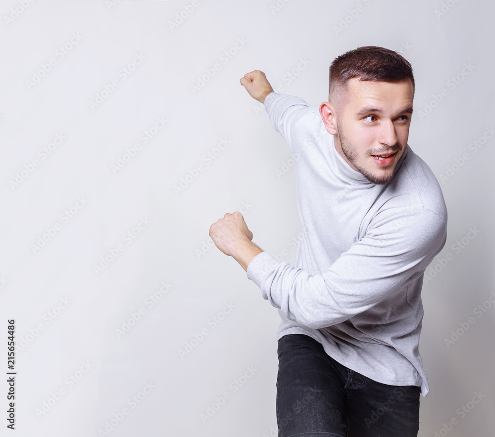 Half side view of handsome young bearded man start funny running like a super hero or character cartoon, on gray background copy space