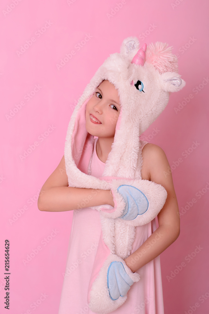 Fototapeta premium little girl in a hat with unikorn on a pink background.
