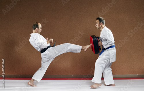 A sportsman with a black belt beats his kick on the simulator