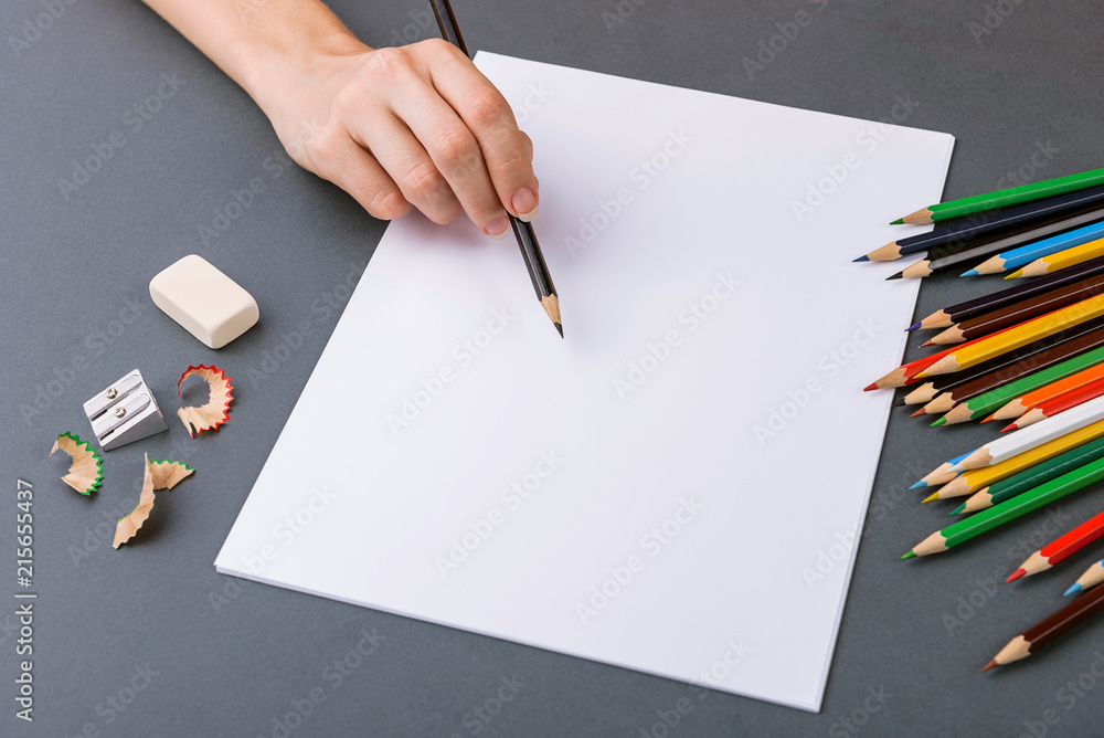 hand with a pencil on a gray background and a set of colored pencils series hand with a pencil on a gray background and a set of colored pencils series