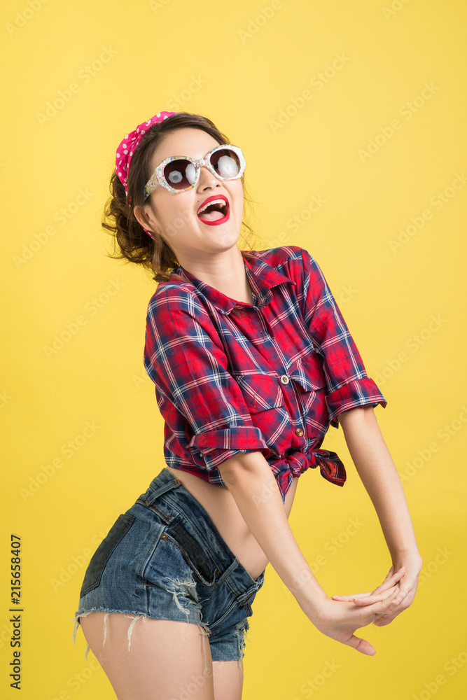 Asian woman retro portrait with pin-up make-up and hairstyle posing over yellow background.