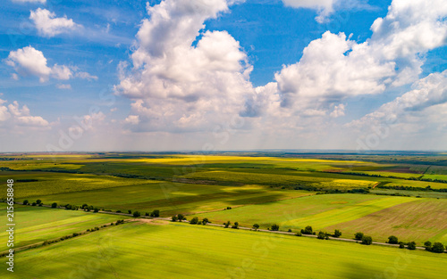 Aerial shot of beautiful agriculture fields with blue skies and fluffy clouds in summer. Cloud shadow on the ground