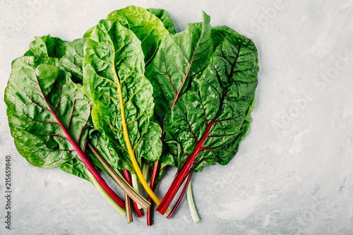 Fotografija Fresh raw swiss rainbow chard leaves on gray stone background.