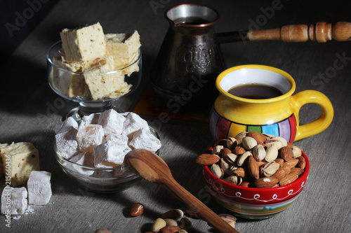 A mug of coffee and different oriental sweets: turkish delight, halva, almond and pistachio photo