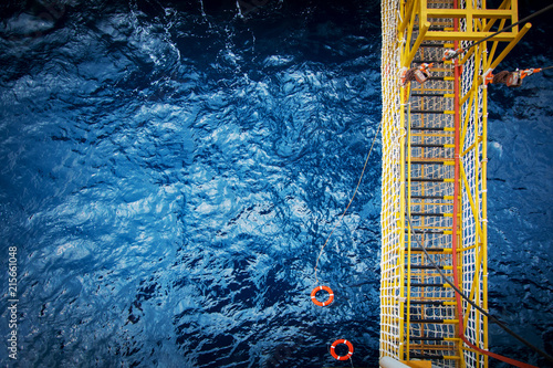 View of an offshore crew walking at the gangway to offshore drilling rig with life life buoys photo