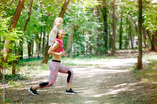 Mother and daughter exercise together in park. Piggyback, Sport, Family, Healthy lifestyle