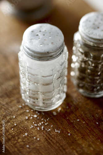 Vintage Cut Glass Salt and Pepper Shakers on Wooden Tabletop with Spilled Salt on Table