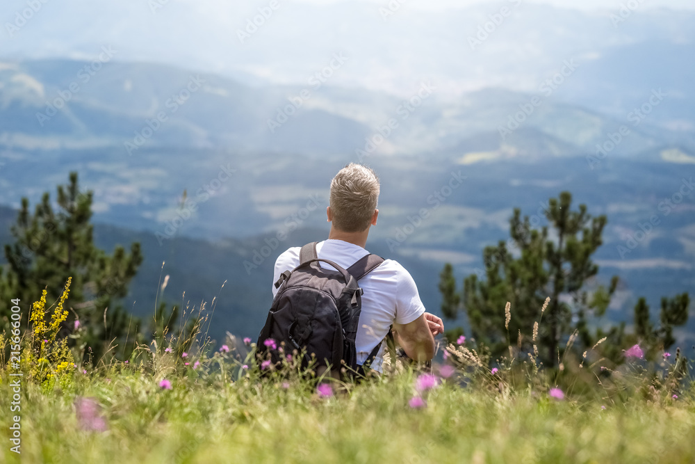 Rear view of young tourist relaxing in grass on the top of the mountain Rear view of young tourist relaxing in grass on the top of the mountain