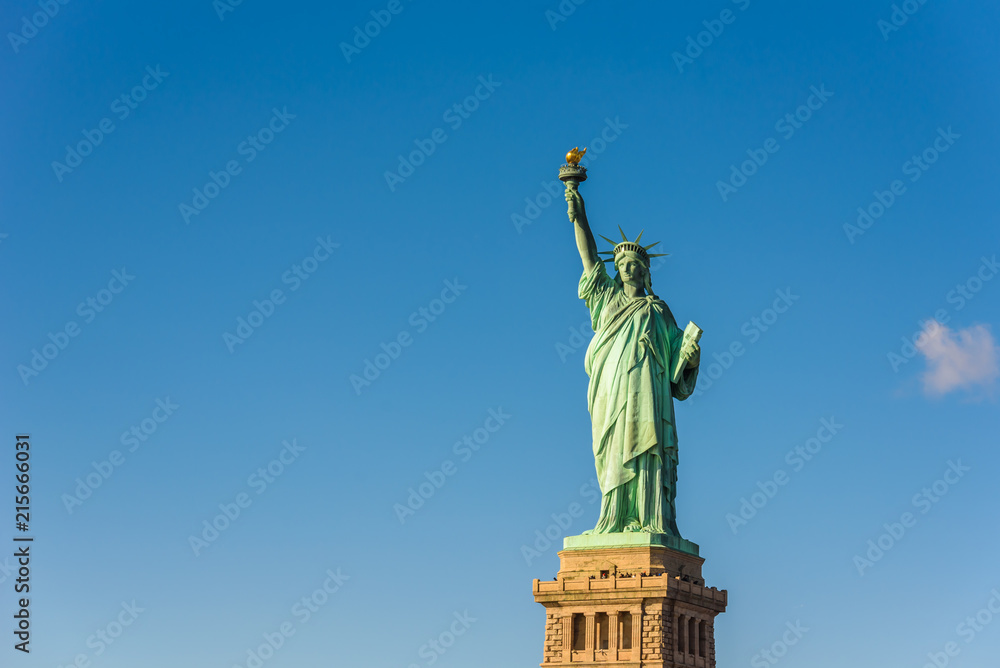 Fototapeta premium Statua Wolności w słoneczny dzień z błękitnym niebem, Nowy Jork, USA