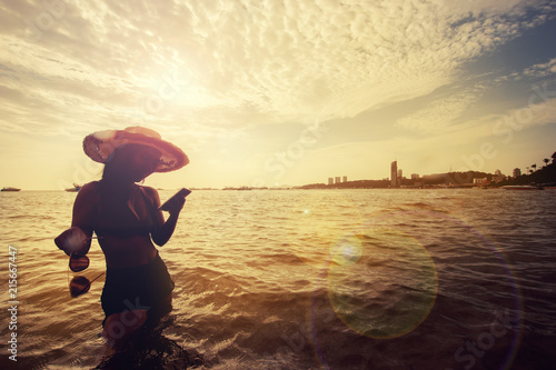 Silhouette Beautiful Asian woman in bikini  play telephone at the sea 