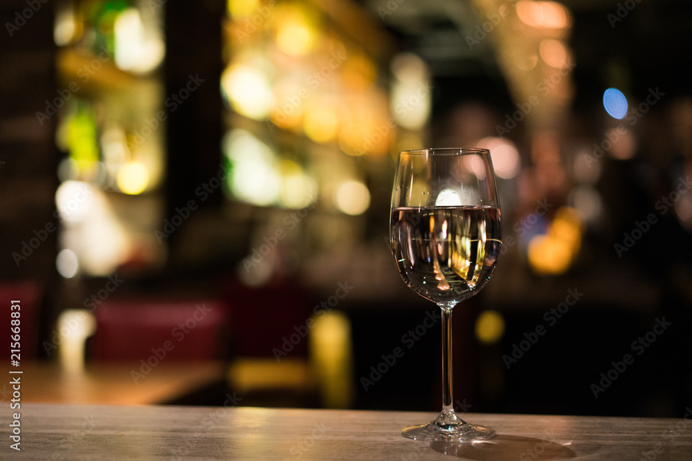 A glass of white wine on the bar counter