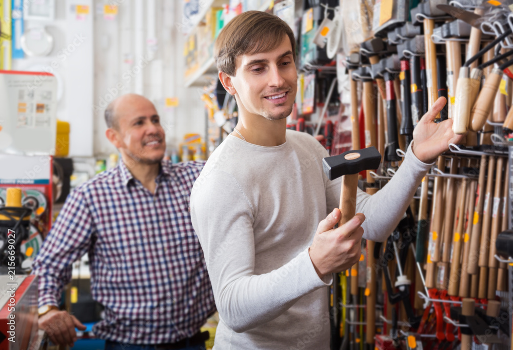 Customer choosing hammer in household store Customer choosing hammer in household store