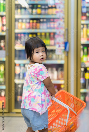 little girl hold the basket and walking in minimart to shopping