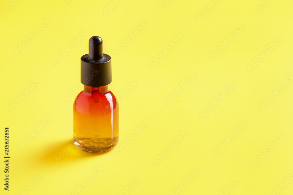 Glass bottle for cosmetics, serums and oils with a pipette on a yellow background. Glass bottle for cosmetics, serums and oils with a pipette on a yellow background.