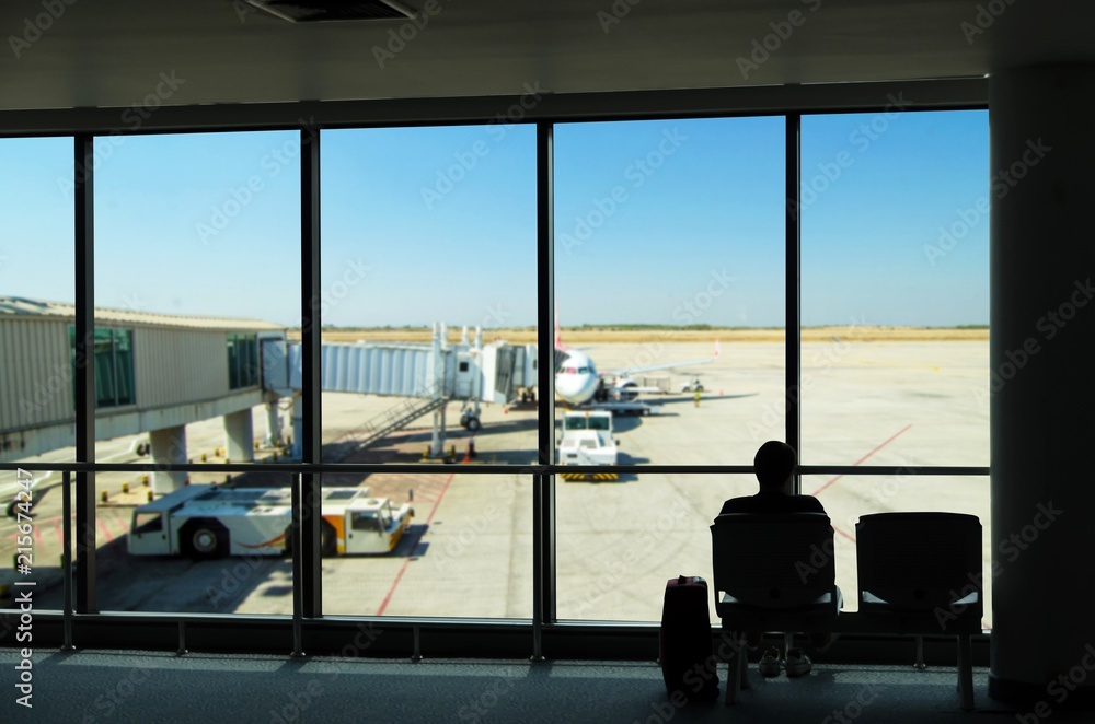 silhouette of business tourist people with luggage looking at airplanes and waiting at the plane boarding gates before departure in airport, travel, lifestyle and transportation