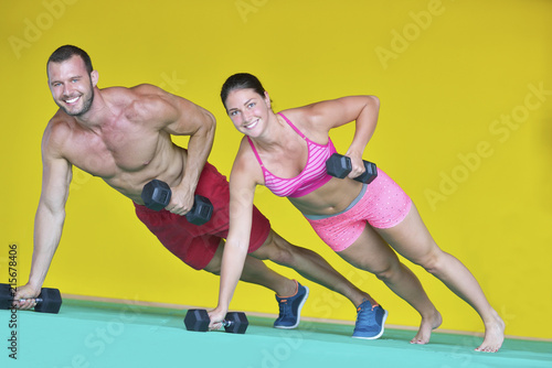 Beautiful fitness young sporty couple doing push ups together indoors.