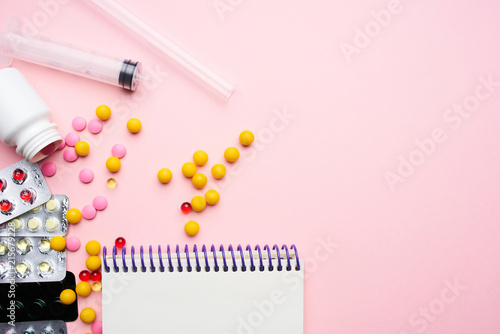 syringe colored pills on pink background