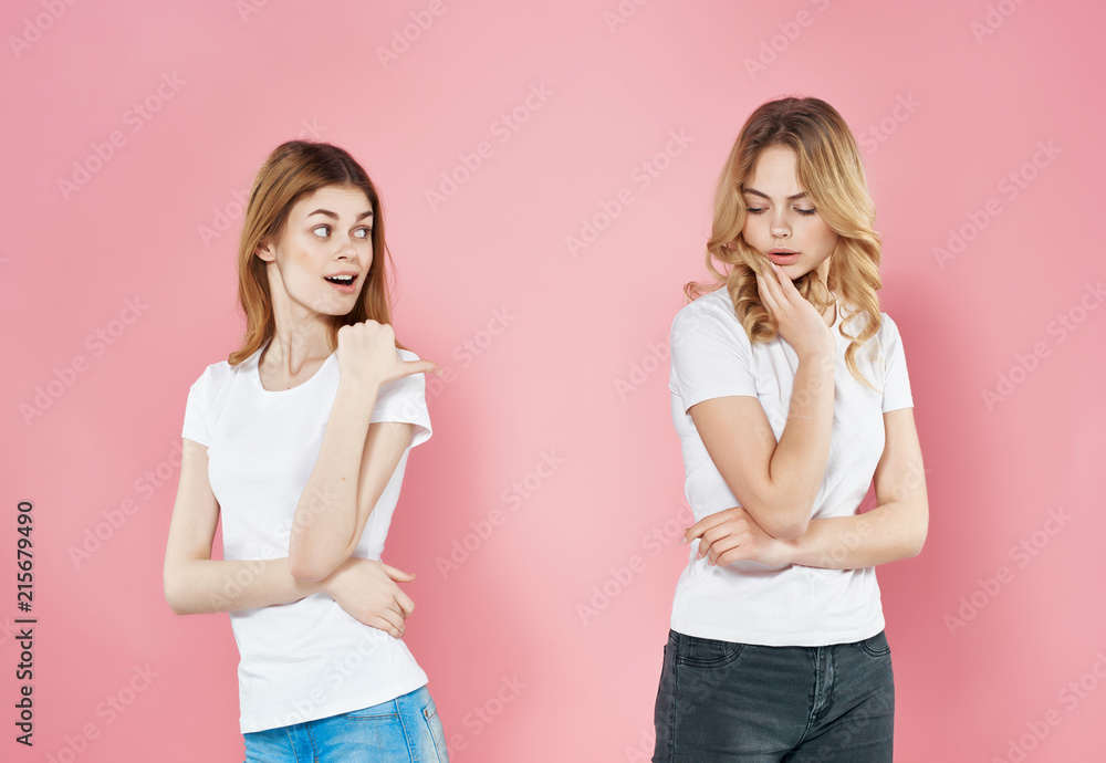 women in white T-shirts look at a free place on a pink background women in white T-shirts look at a free place on a pink background