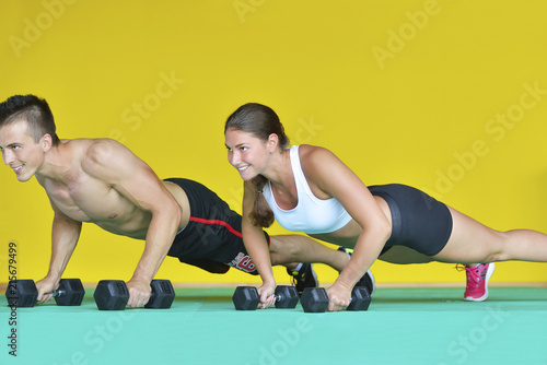 Beautiful fitness young sporty couple doing push ups together indoors.