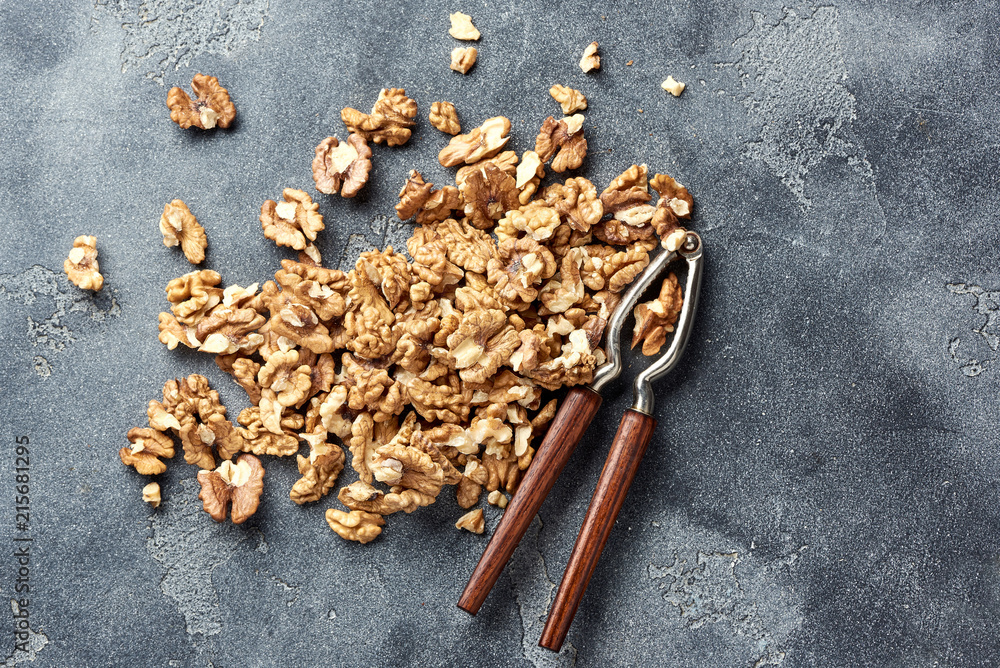 Walnut kernels in clay bowl. Nuts and nutcracker on gray background. Top view. Walnut kernels in clay bowl. Nuts and nutcracker on gray background. Top view.